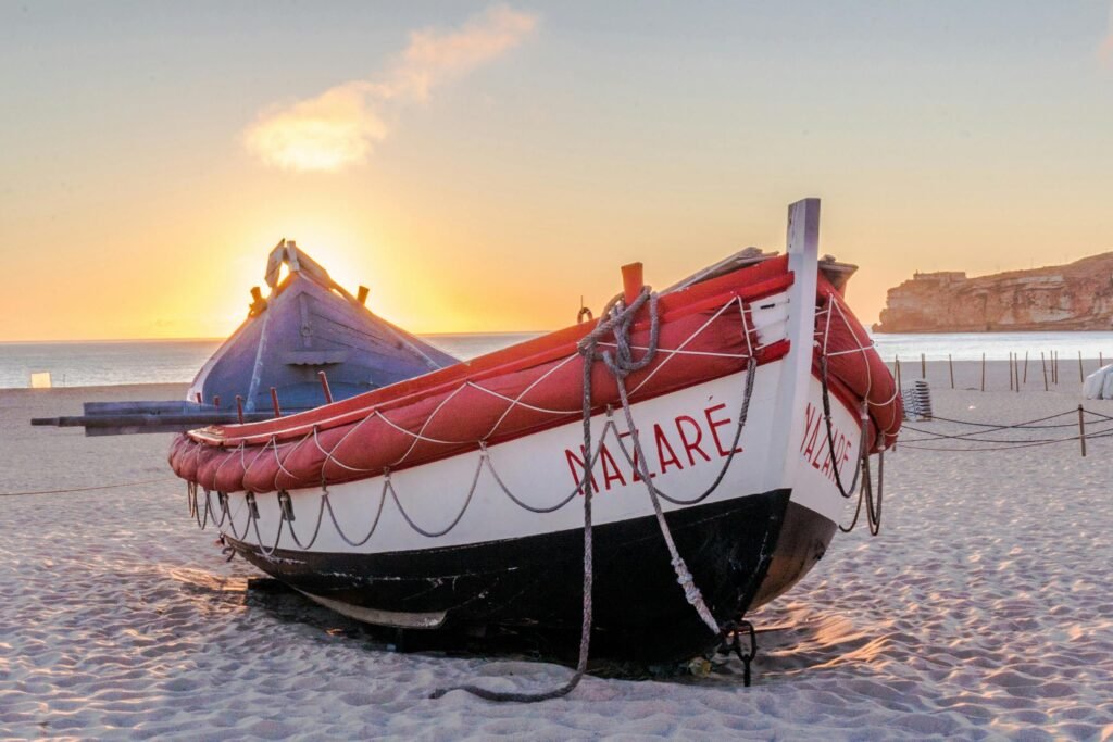 Traditional Portuguese boat on Nazaré beach at sunset, showcasing vibrant colors and serene atmosphere.